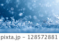 A close-up of delicate snowflakes glistening on a frosty surface, bathed in soft blue light and surrounded by bokeh, creating a serene and enchanting winter wonderland backdrop 128572881