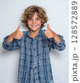 Energetic young boy gives a double thumbs-up, showcasing a positive, approving gesture. His blue eyes, genuine smile convey enthusiasm, success, perfect for conveying approval, achievement 128572889