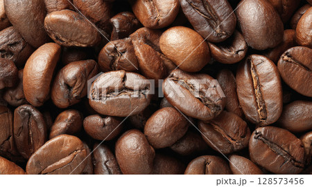 Dark roasted coffee beans creates textured background. Ideal for themes related to coffee, beverages, cafes, breakfast, energy, natural organic products, highlighting rich aroma, robust flavor. 128573456