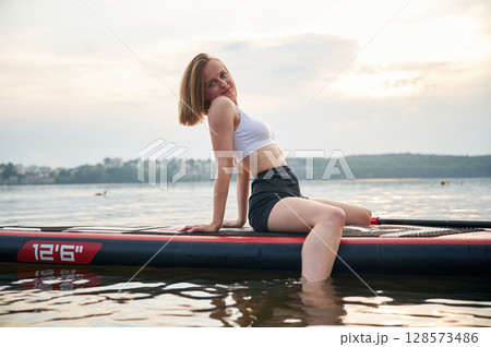 Sitting and relaxing. Young woman is on sup boards in the lake 128573486