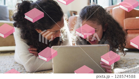Pink book icons in seamless motion against caucasian mother and daughter using digital tablet Pink book icons in seamless motion against caucasian mother and daughter using digital tablet 128574588