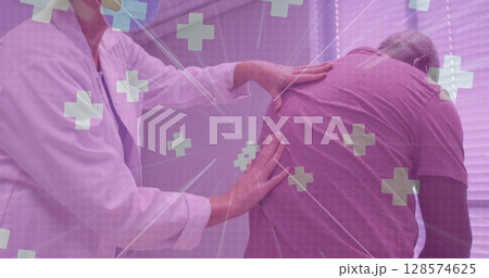 Multiple medical symbol floating against doctor examining back of senior man at hospital 128574625