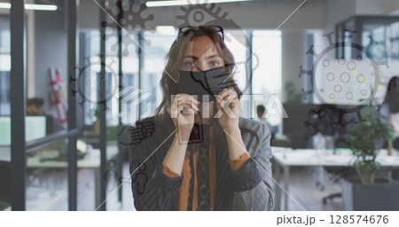 Image of medical icons over caucasian businesswoman wearing face mask 128574676