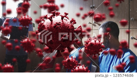 Image of virus cells over diverse group of male football players with coach in changing room 128574686