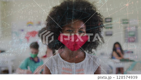 Image of mathematical equations over diverse schoolchildren wearing face masks 128574939