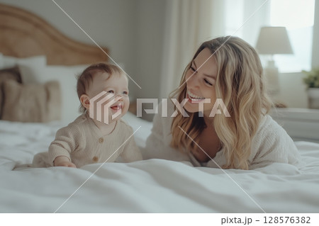 Joyful Moments Between Mother and Baby on a Cozy Bed in a Sunlit Bedroom 128576382