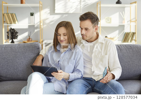 Happy spouses, smiling couple in love using tablet computer together at home, talking on video call 128577034