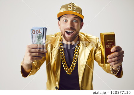 Surprised Rich Man In Golden Suit Holding Stack Of Cash And Gold Bar 128577130