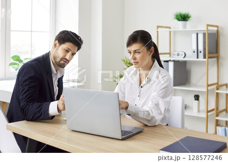 Two business people having meeting, looking at laptop monitor screen and analyzing financial data. Two business people having meeting, looking at laptop monitor screen and analyzing financial data. 128577246