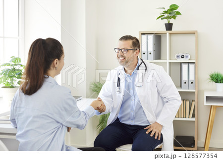 Male Doctor Or Nurse Shaking Hands With Female Patient In Hospital 128577354