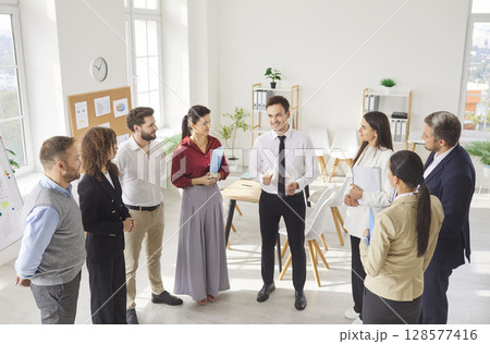 Businesspeople, leader praising colleagues at group meeting in modern office, diverse coworkers meet 128577416
