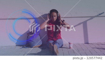 Image of scope scanning over biracial woman sitting and wearing headphones 128577442