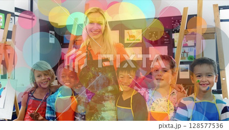 Image of spots over happy caucasian female teacher painting with diverse schoolchildren 128577536