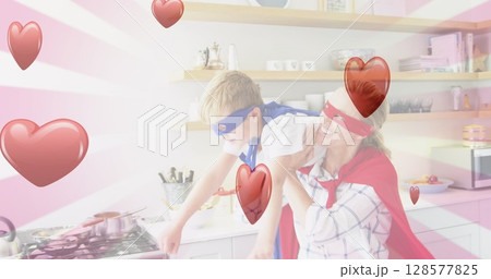 Image of hearts falling over caucasian woman and her son playing together in kitchen 128577825