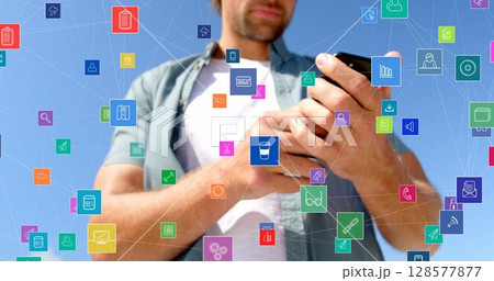 Image of network of connections with icons over caucasian man using smartphone outdoors 128577877