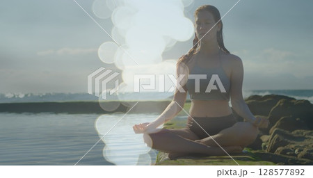 Image of light spots over caucasian woman practicing yoga and meditating Image of light spots over caucasian woman practicing yoga and meditating 128577892