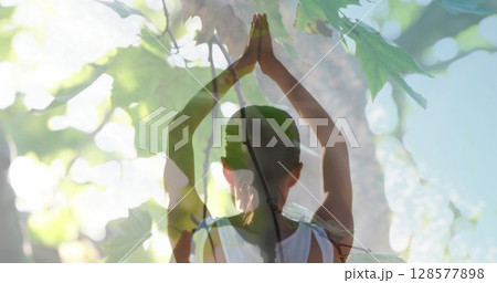 Image of leaves over caucasian woman practicing yoga and meditating 128577898