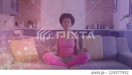 Image of light spots over african american woman practicing yoga and meditating at home 128577932
