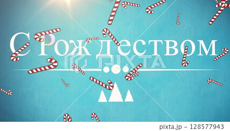 Image of seasonal christmas greeting in cyrillic text, with falling striped candy canes, on blue 128577943
