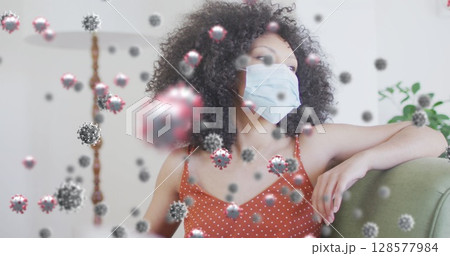 Image of virus cells over african american woman with face mask 128577984