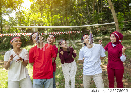 Portrait of an Indonesian southeast asian people celebrate Indonesia Independence Day on the 17th of August with a game of biting coins in eggplant outdoors. Concept of Kemerdekaan Indonesia Portrait of an Indonesian southeast asian people celebrate Indonesia Independence Day on the 17th of August with a game of biting coins in eggplant outdoors. Concept of Kemerdekaan Indonesia 128578666