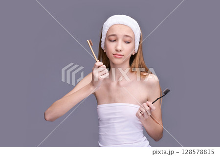 Young caucasian female comparing bamboo and plastic toothbrush for sustainable Young caucasian female comparing bamboo and plastic toothbrush for sustainable 128578815