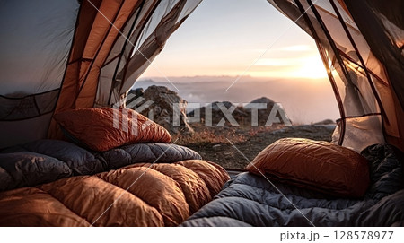 Camping tent open to mountain vista at sunset with sleeping bags 128578977