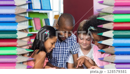 Image of pencils over diverse schoolchildren using tablet and smiling 128579381
