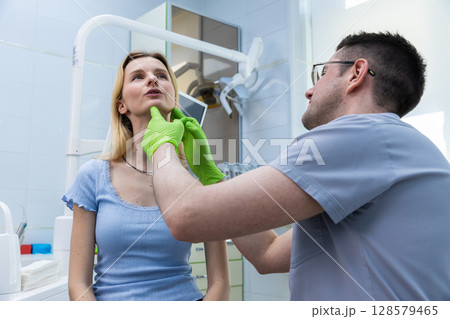 A Young Woman and a Dentist in a Clinical Setting, Engaging in a Careful Examination of Facial Features with Focused Attention for Optimal Health and Aesthetics in Modern Dentistry A Young Woman and a Dentist in a Clinical Setting, Engaging in a Careful Examination of Facial Features with Focused Attention for Optimal Health and Aesthetics in Modern Dentistry 128579465
