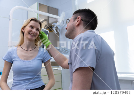 Friendly Interaction in a Dental Clinic: A Patient Smiling While Receiving Care from a Dentist in a Bright and Modern Dental Office Environment 128579495