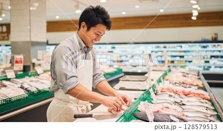 鮮魚コーナーで楽しそうに働く男性スタッフ 128579513