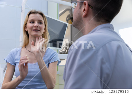 A Young Woman Engaging in Conversation with a Dentist in a Modern Dental Clinic Setting While Discussing Oral Health and Treatment Options with a Friendly Approach 128579516