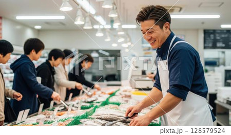鮮魚コーナーで笑顔で働く男性店員と買い物客 128579524