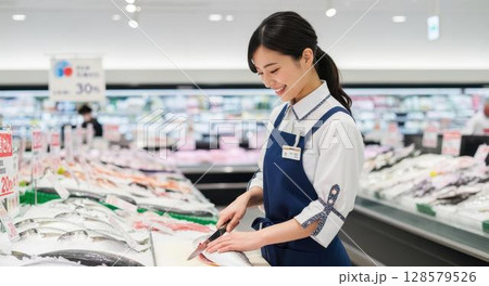 楽しそうに魚を調理する魚屋の女性スタッフ 128579526