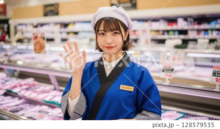 スーパーの鮮魚売り場で笑顔で手を振っている女性店員 128579535