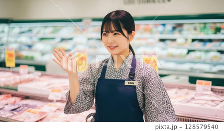スーパーの鮮魚売り場で笑顔で手を振って挨拶する女性店員 128579540