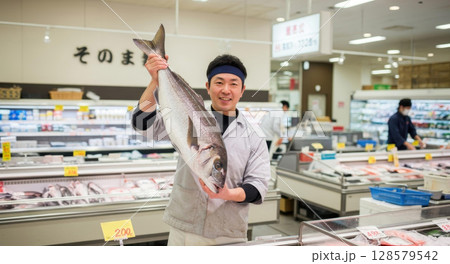笑顔で獲れたての魚をおすすめするスーパーの男性スタッフ 128579542
