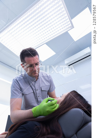 A Cosmetic Procedure in Progress: A Healthcare Professional Administering Treatment to a Patient with Care and Precision in a Bright Clinic Environment 128579567