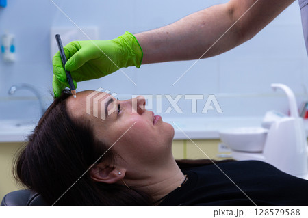 Expert Preparation for Cosmetic Procedure: Professional Applying Markings with Precision to Enhance Client's Natural Features in Modern Aesthetic Environment 128579588