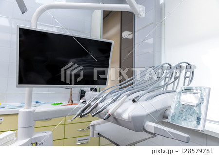 Modern Dental Clinic Equipment Showcasing Advanced Technology with Monitor and Dental Tools for Professional Care in a Clean Environment 128579781