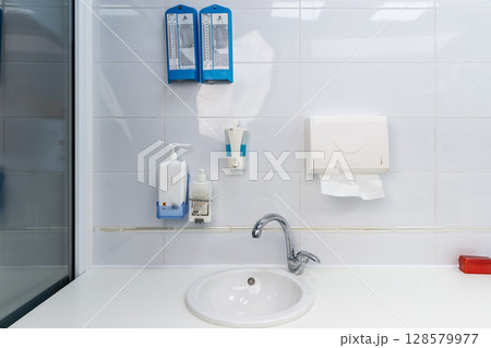 Modern Restroom Setup Featuring Hand Sanitizer and Paper Towel Dispenser in a Light-Colored Environment with Basic Amenities for Improved Hygiene and Convenience 128579977