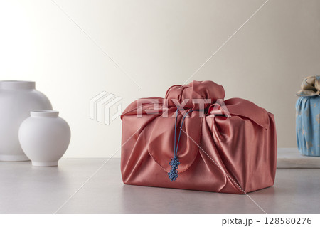 Elegant Korean table setting with traditional Korean bojagi gift wrapping for Chuseok, ceramic vase and fabric, tree branches. 128580276