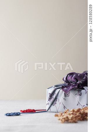 Elegant Korean table setting with traditional Korean bojagi gift wrapping for Chuseok, ceramic vase and fabric, tree branches. 128580289