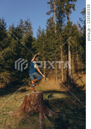 Fit sporty happy young woman wearing sportswear meditating doing yoga breathing stretching exercises standing in nature park outdoors in sunny morning. Authentic candid photo. 128580338