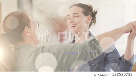 Image of white spots of light over caucasian female gay couple dancing in background Image of white spots of light over caucasian female gay couple dancing in background 128580752