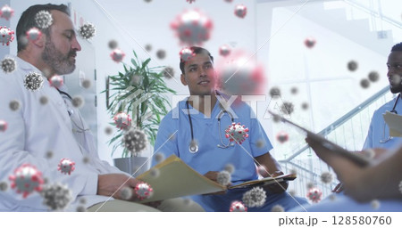 Diverse medical team reviewing files and discussing pandemic response in clinic with virus overlays 128580760