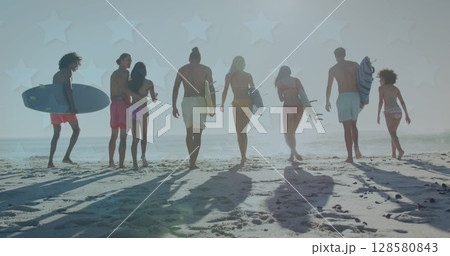 Image of stars over back of diverse friends walking on beach with surfingboards 128580843