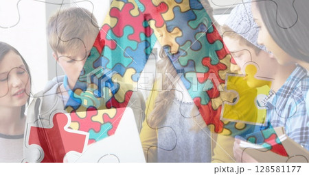 Image of puzzle pieces over diverse schoolchildren using laptop 128581177