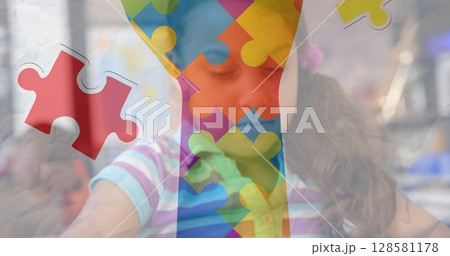 Image of puzzle pieces and hand over biracial schoolgirlusing tablet 128581178