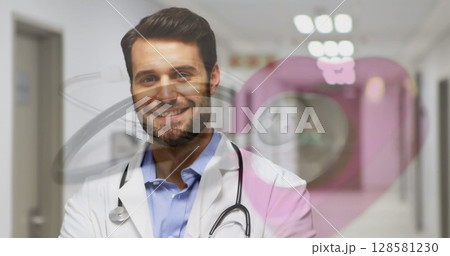 Image of stethoscope over happy caucasian male doctor in hospital 128581230